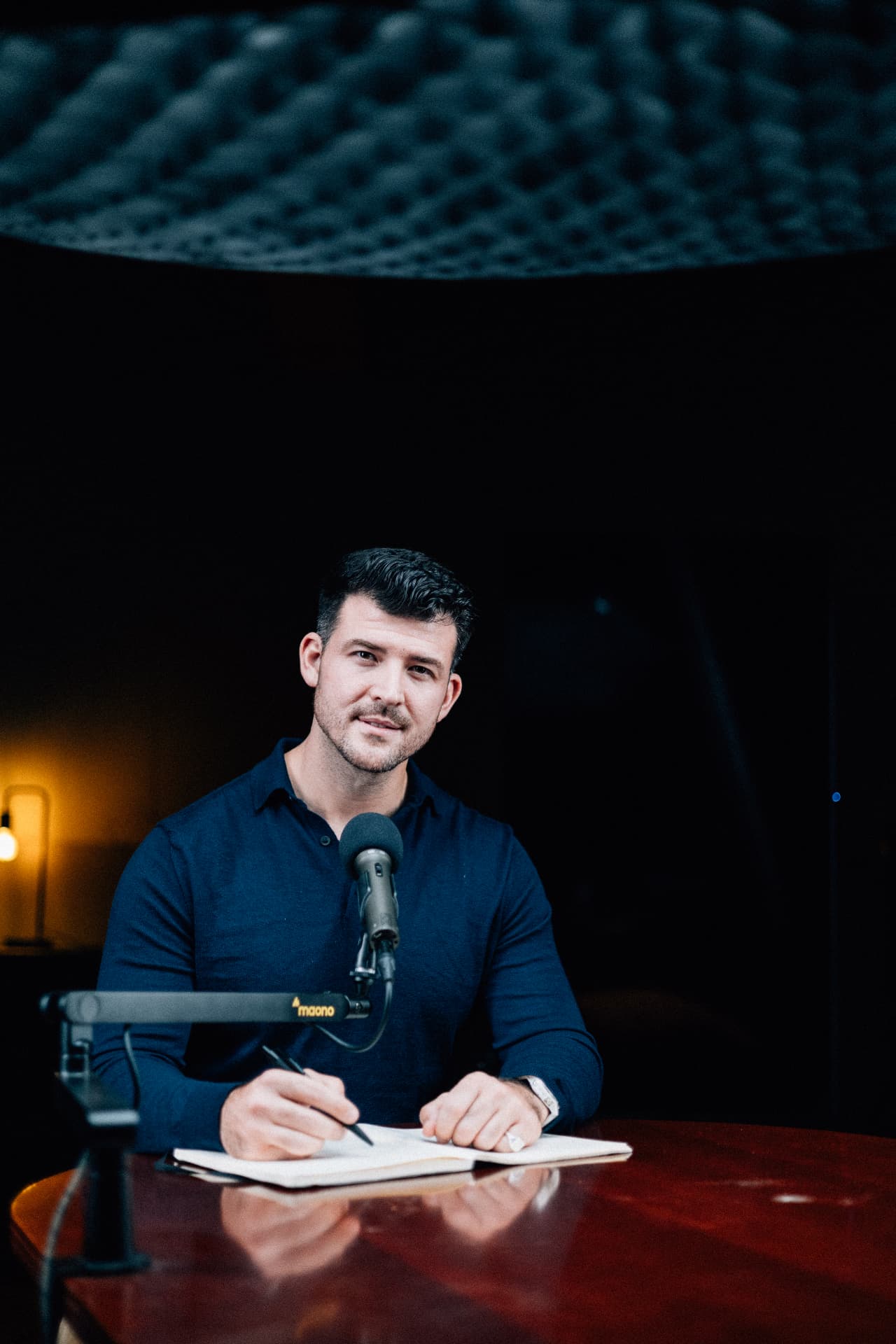 Eric Smith sitzt bei einem Podcast-Interview am Studiotisch und macht Notizen